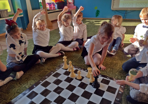 Dzieci biją królem figury i pionki na szachownicy